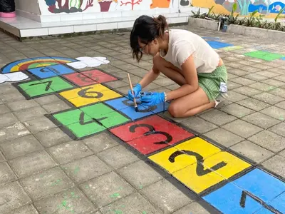 Volunteer painting a hopscotch game on a school playground in Bali