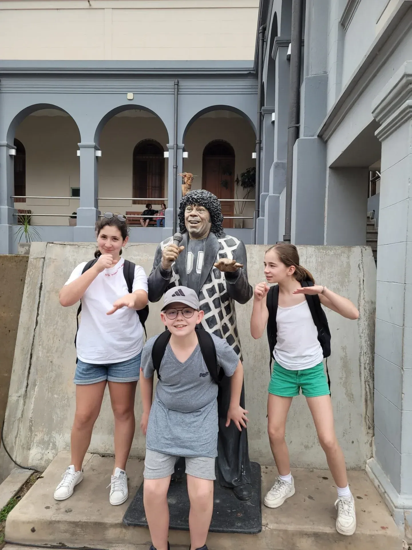 Teenagers posing with a statue in front of a colonial building in Cordoba, Argentina