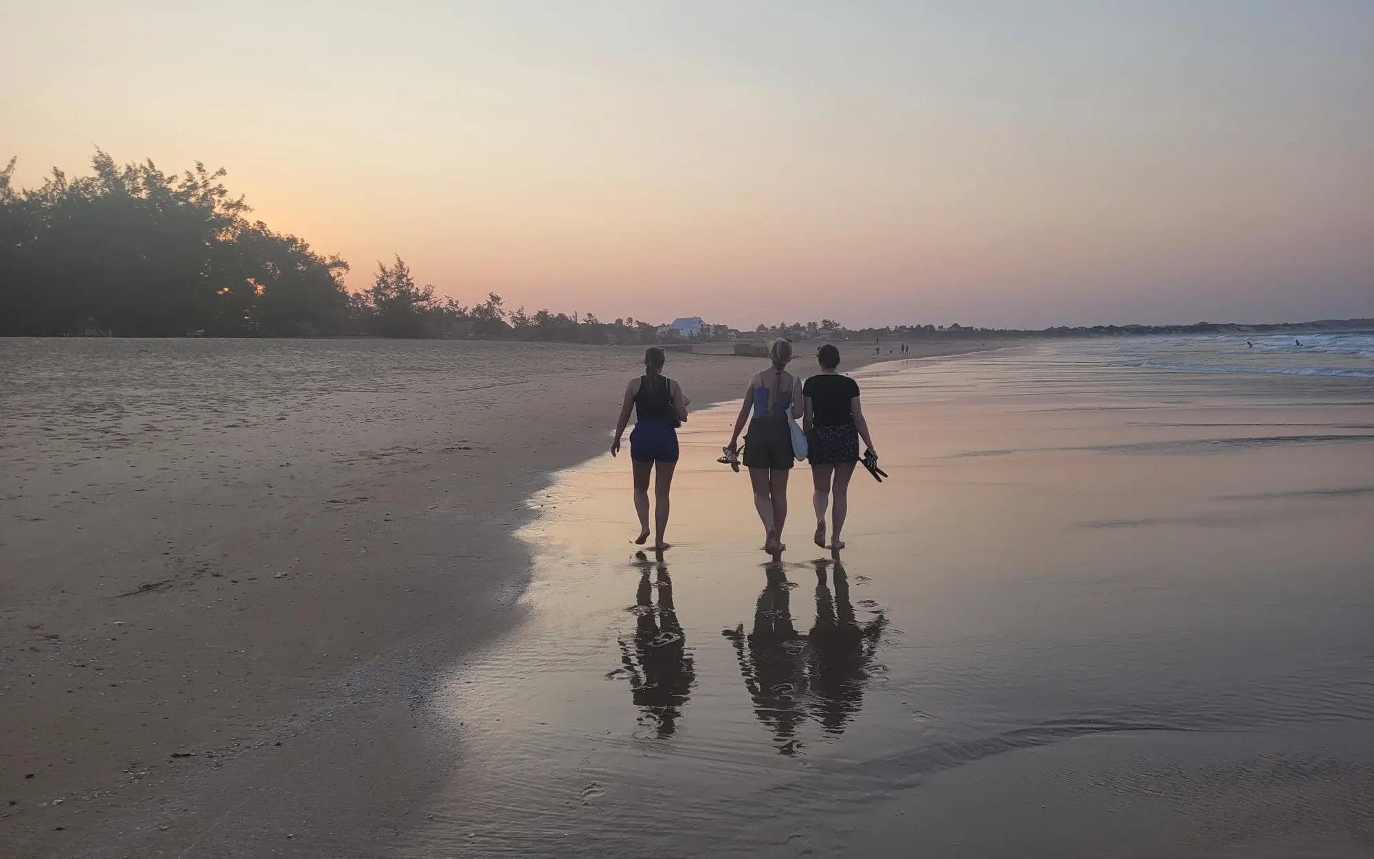 Three people walking along the beach at sunset in Fiji