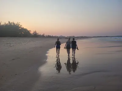 Three people walking along the beach at sunset in Fiji