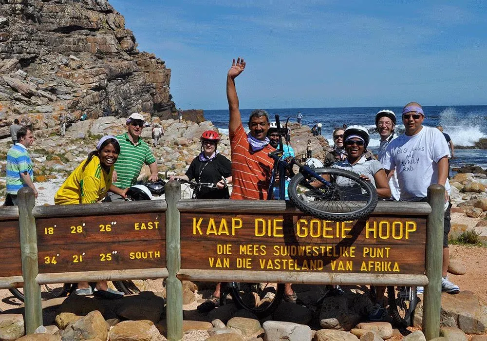 Group of cyclists celebrating at the Cape of Good Hope sign, South Africa