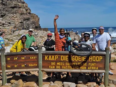 Group of cyclists celebrating at the Cape of Good Hope sign, South Africa