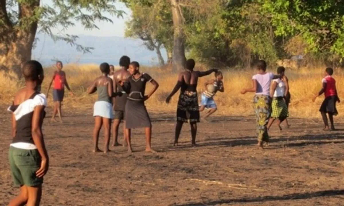 Children playing a game on dusty ground at sunset in Malawi
