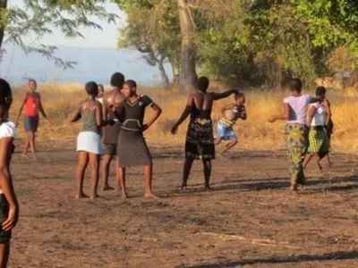 Children playing a game on dusty ground at sunset in Malawi