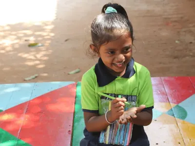 Smiling young girl drawing at a school in India
