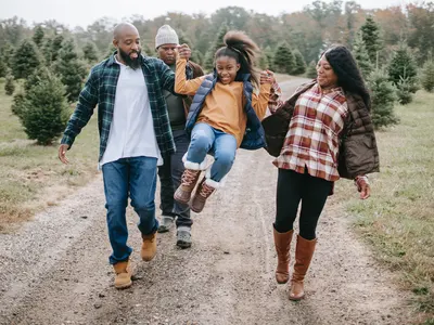 Family walking along a farm track, parents swinging their daughter between them