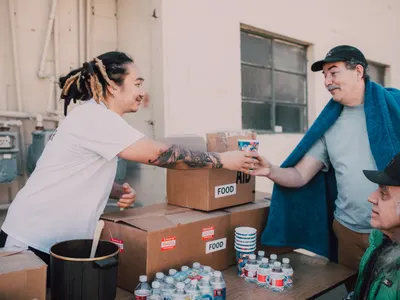 Volunteer handing a drink to a man at a food distribution point