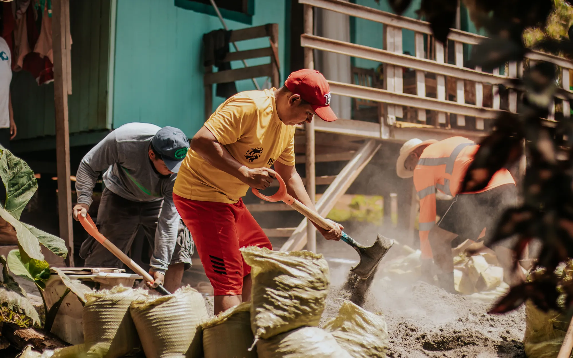 Volunteers shovelling sand into bags on an outdoor work site