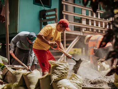 Volunteers shovelling sand into bags on an outdoor work site