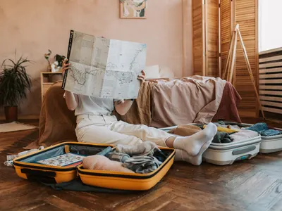 Traveller reading a map beside open suitcases while packing