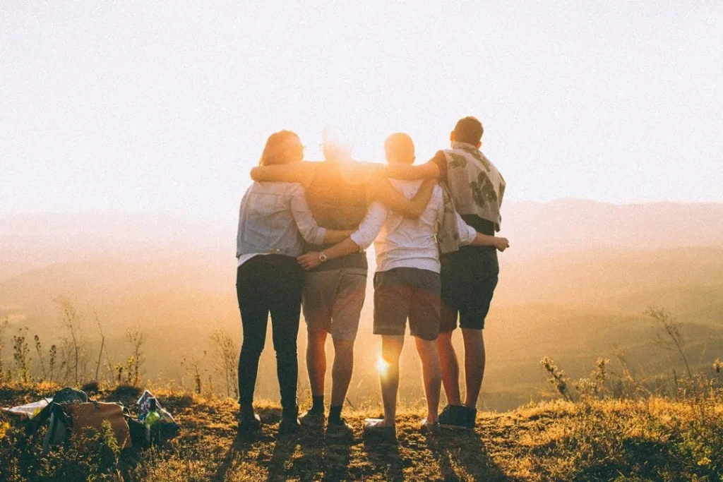 Quatre jeunes réunis face à un paysage au coucher du soleil