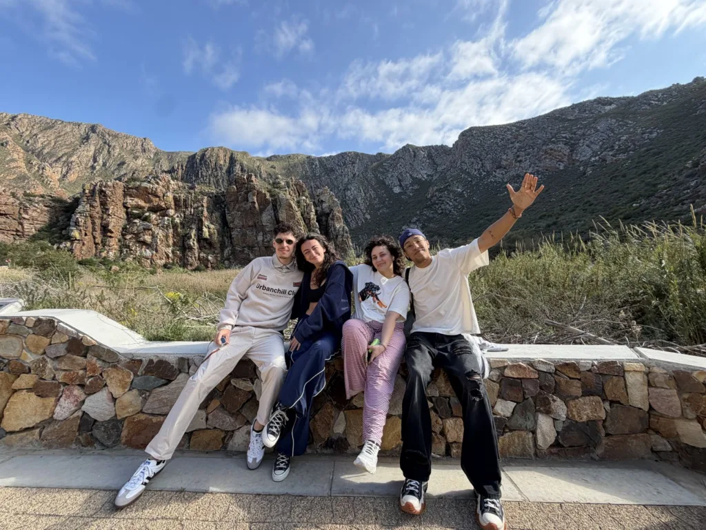 Quatre participants assis sur un muret devant les montagnes en Afrique du Sud